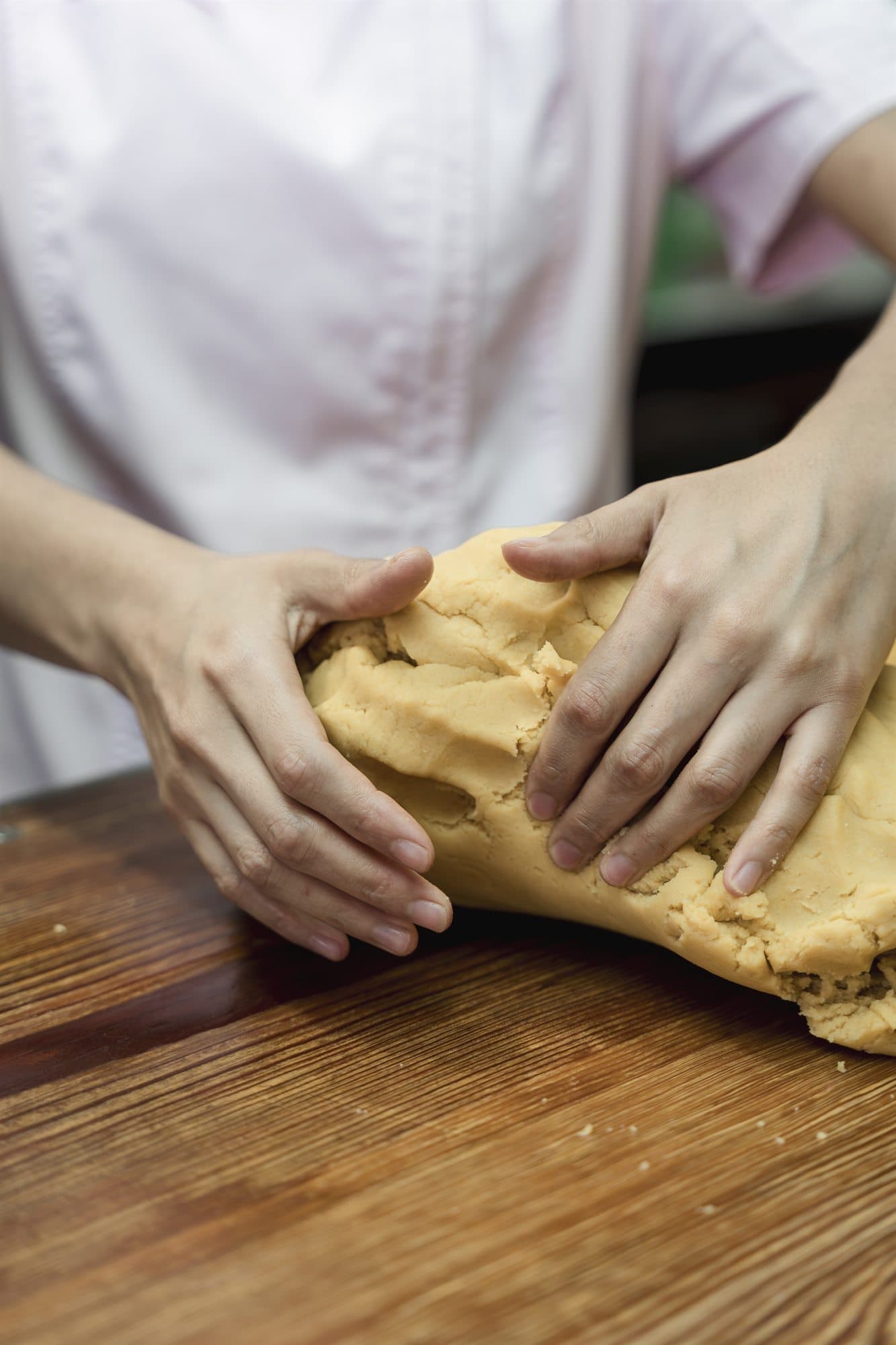 Manos amasando masa sobre una mesa de madera
