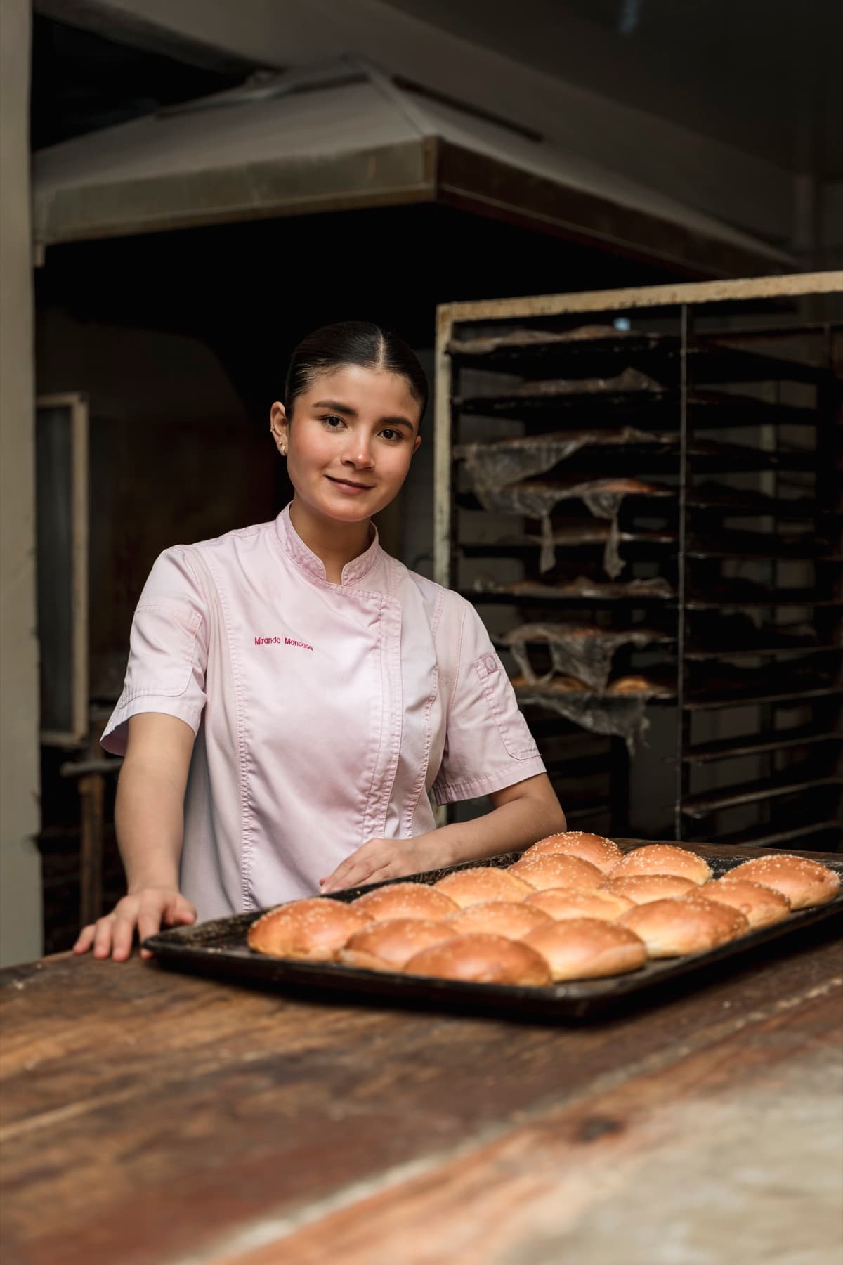 Miranda Moncada sosteniendo una charola de pan recién horneado en una panadería tradicional